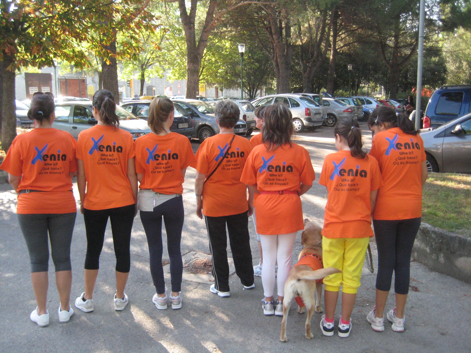 Squadra Xenia di spalle con t-shirt arancioni e logo Xenia stampato sulla schiena